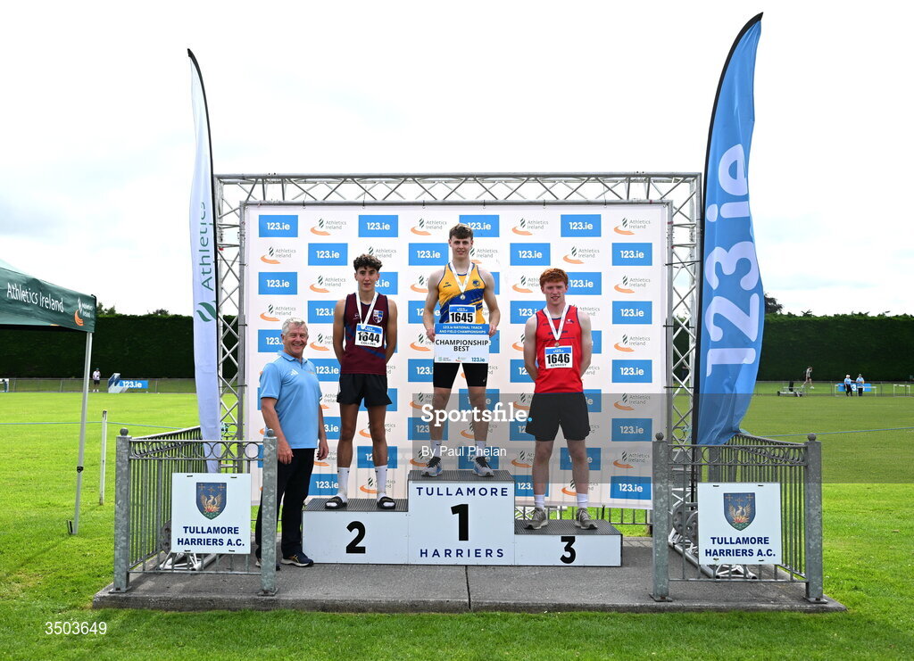 5 July 2026; Darragh Fahy of Loughrea A.C., centre, in first, Alex Collins of Lios Tuathail A.C., left, in second and Jamie Kennedy of Tír Chonaill A.C., right, in third, alongside Chair of Competition Commission Micael Quinlan after in the U20 men's Triple Jump during day two of the 123.ie National U20 & U23 Track & Field Championships at Tullamore Harriers Athletics Club in Tullamore, Offaly. Photo by Paul Phelan/Sportsfile