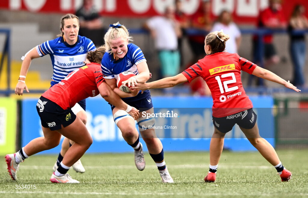 8 August 2026; Roisín Kinch of Leinster is tackled by Munster players Enya Breen, left, and Lucia Linn during the Vodafone Womens Interprovincial Championship Round 1 match between Munster and Leinster at Virgin Media Park in Cork. Photo by Shauna Clinton/Sportsfile
