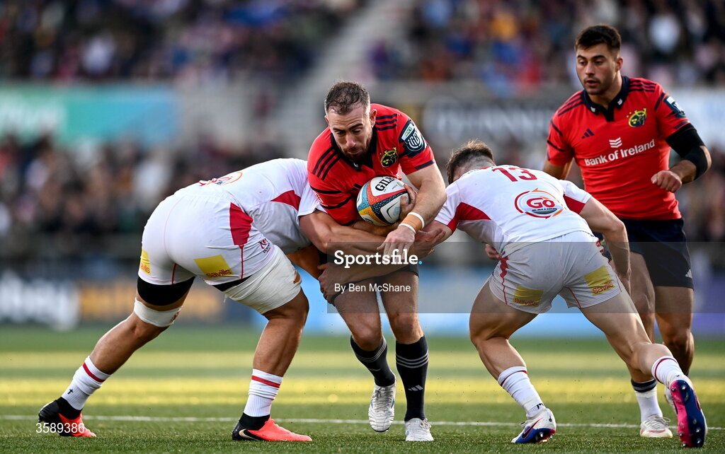 10 October 2026; JJ Hanrahan of Munster is tackled by Juarno Augustus, left, and Jamie Benson of Ulster during the United Rugby Championship match between Ulster and Munster at Affidea Stadium in Belfast. Photo by Ben McShane/Sportsfile