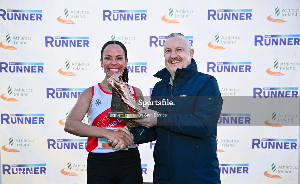 18 October 2026; Lisa Madden of Sportsworld AC, Dublin, is presented with the Jim McNamara Trophy by Shane McNamara after winning the Master Women 6000m during the Autumn Open Cross Country International at the Sport Ireland Campus in Dublin. Photo by Sam Barnes/Sportsfile