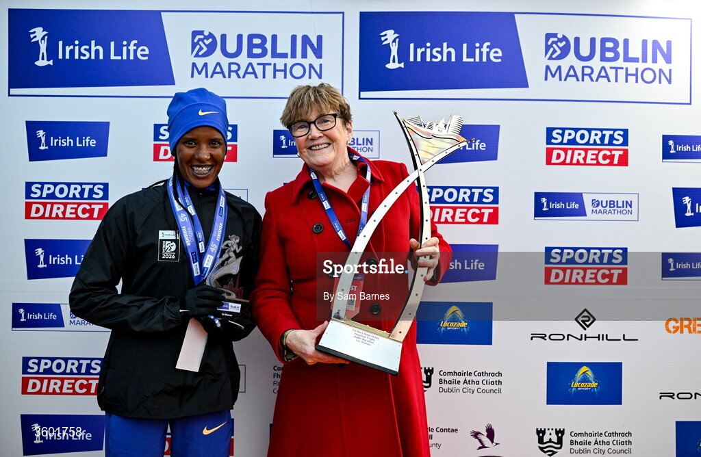 25 October 2026; Women's overall winner Zenebu Fikdau Jebesa of Ethiopia is presented the Mary Nolan-Hickey cup by Mary Nolan-Hickey during the 2026 Irish Life Dublin Marathon, as thousands of runners took to the streets of Dublin for the 45th running of the event. Photo by Sam Barnes/Sportsfile