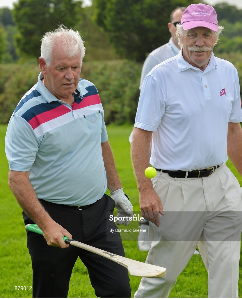 18 June 2014; Gerry McIlroy, father of Rory McIlroy, watched by playing partner Dermot Desmond, plays with a golf ball and hurley on the 9th fairway during the 2014 Irish Open Golf Championship Pro-Am. Fota Island, Cork. Picture credit: Diarmuid Greene / SPORTSFILE