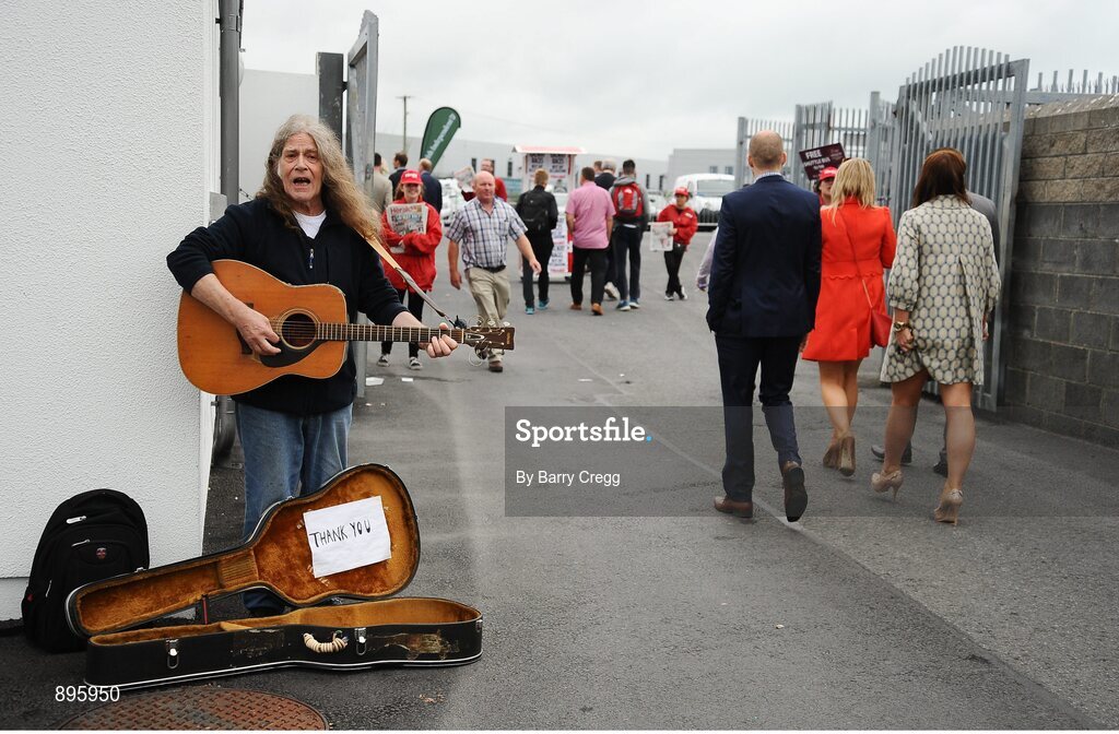 31 July 2014; A general view of a busker playing as racegoers exit the track after the days races. Galway Racing Festival, Ballybrit, Co. Galway. Picture credit: Barry Cregg / SPORTSFILE