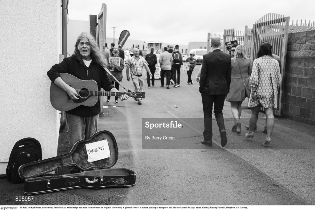31 July 2014; (Editors please note; This black & white image has been created from an original colour file) A general view of a buscar playing as racegoers exit the track after the days races. Galway Racing Festival, Ballybrit, Co. Galway. Picture credit: Barry Cregg / SPORTSFILE