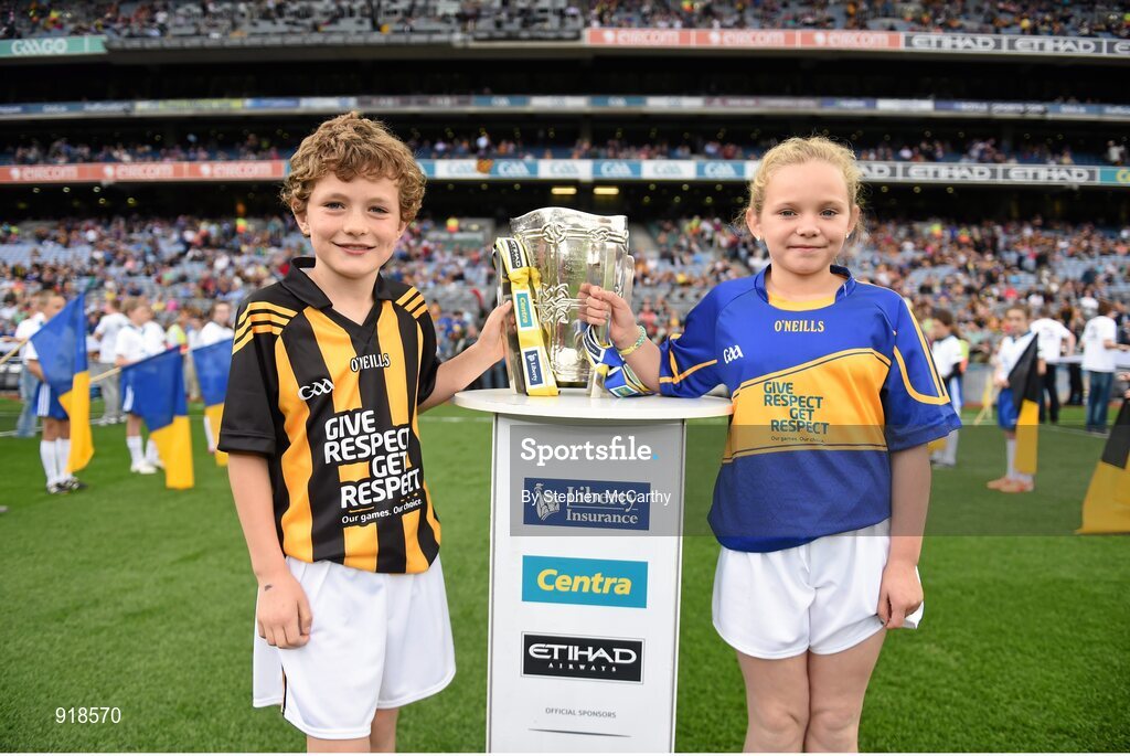 27 September 2014; Roísín O'Meara, Narnane NS, Tipperary, and Alex Cass, Thomastown NS, Kilkenny, carry the Liam MacCarthy cup onto the pitch ahead of the game. GAA Hurling All Ireland Senior Championship Final Replay, Kilkenny v Tipperary. Croke Park, Dublin. Picture credit: Stephen McCarthy / SPORTSFILE
