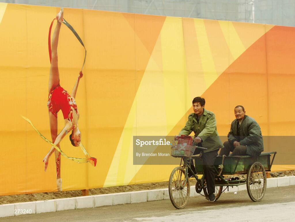 12 November 2007; Locals pass by perimeter fencing near the Beijing University of Technology Gymnasium during preparations in Beijing ahead of the 2008 Summer Olympic Games. The 2008 Summer Olympics, officially known as the Games of the XXIX Olympiad, will be take place from the 8th August 2008 to 24th August 2008, at the Beijing National Stadium in Beijing, China. Beijing, China. Picture credit: Brendan Moran / SPORTSFILE