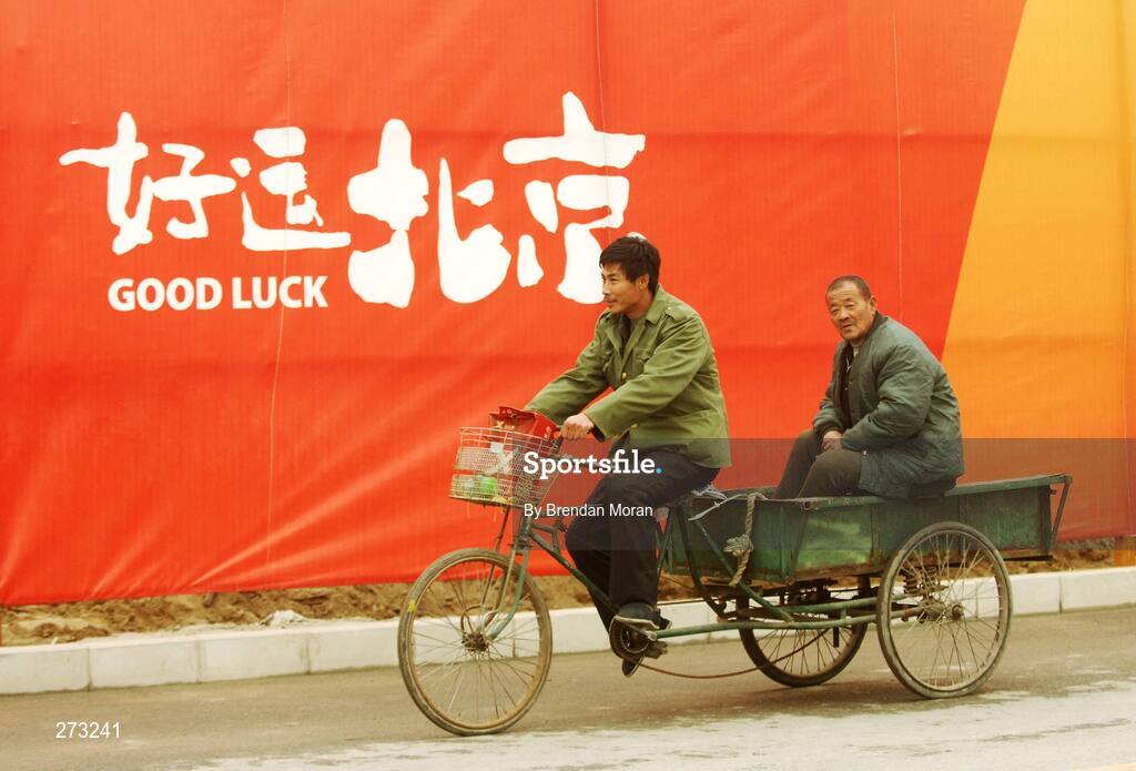 12 November 2007; Locals pass by perimeter fencing near the Beijing University of Technology Gymnasium during preparations in Beijing ahead of the 2008 Summer Olympic Games. The 2008 Summer Olympics, officially known as the Games of the XXIX Olympiad, will be take place from the 8th August 2008 to 24th August 2008, at the Beijing National Stadium in Beijing, China. Beijing, China. Picture credit: Brendan Moran / SPORTSFILE *** Local Caption ***