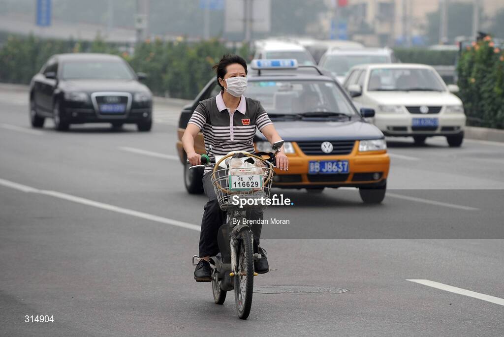 7 August 2008; A general view of a local cycling through the city with a mask on their face. Beijing 2008 - Games of the XXIX Olympiad, Beijing, China. Picture credit: Brendan Moran / SPORTSFILE