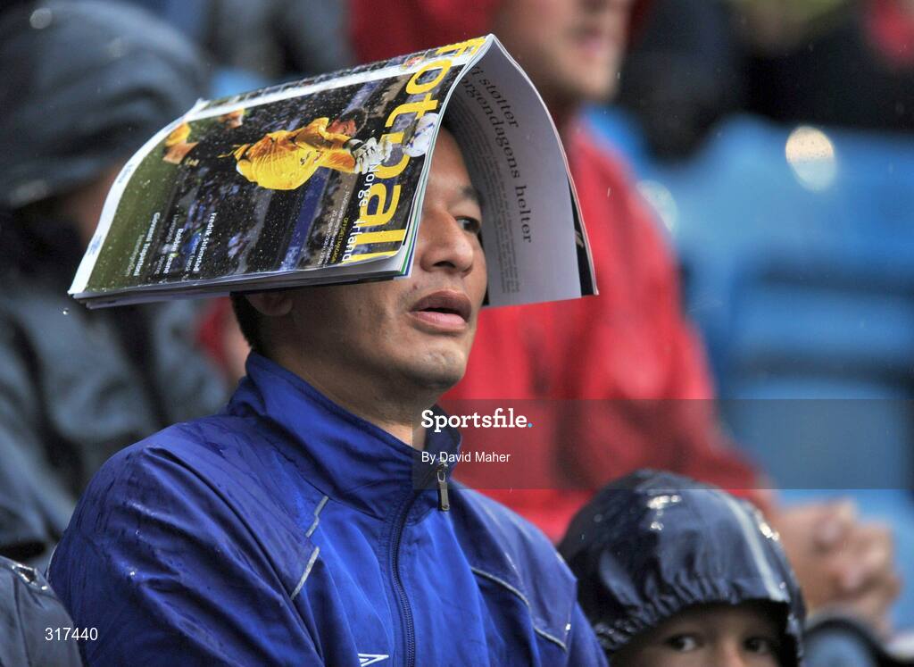 20 August 2008; A spectator uses a match programme to sheild from the heavy rain during the game. International Friendly, Norway v Republic of Ireland, Ullevall Stadium, Oslo, Norway. Picture credit: David Maher / SPORTSFILE