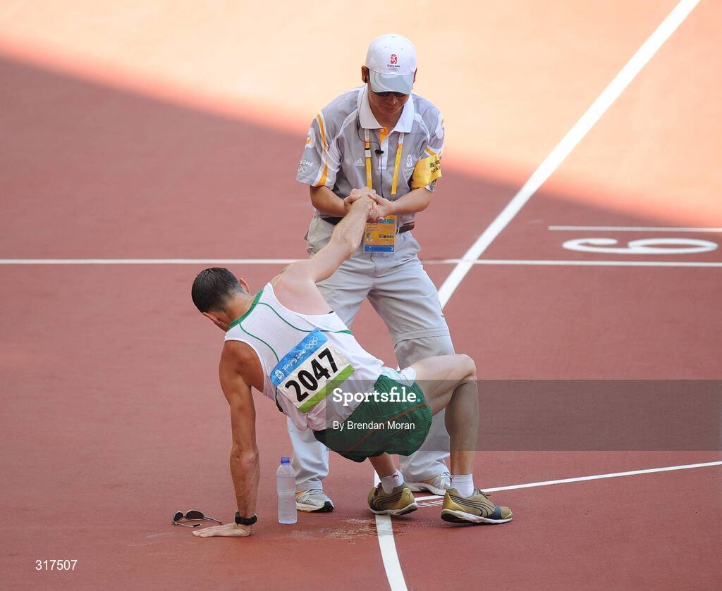 22 August 2008; Jamie Costin, 2047, Ireland, is helped up by an official after the Men's 50km Walk Final, where he finished 44th in a time of 4:15.16. Beijing 2008 - Games of the XXIX Olympiad, National Stadium, Olympic Green, Beijing, China. Picture credit: Brendan Moran / SPORTSFILE