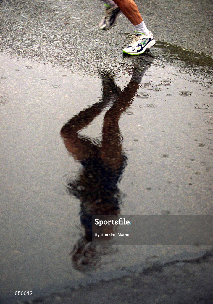 30 October 2000; A runner is reflected in a puddle during the rain soaked 2000 98FM Dublin City Marathon in Dublin. Photo by Brendan Moran/Sportsfile