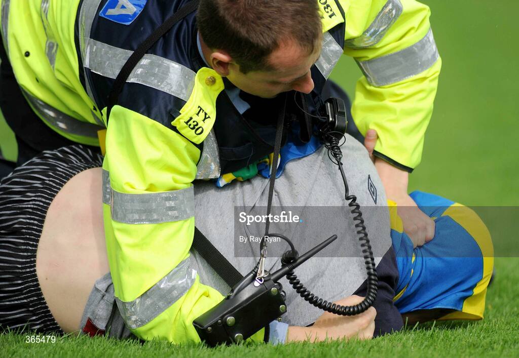 12 July 2009; A Tipperary fan is tackled to the ground by a Garda, after running onto the pitch during the match. GAA Hurling Munster Senior Championship Final, Tipperary v Waterford, Semple Stadium, Thurles, Co. Tipperary. Picture credit: Ray Ryan / SPORTSFILE