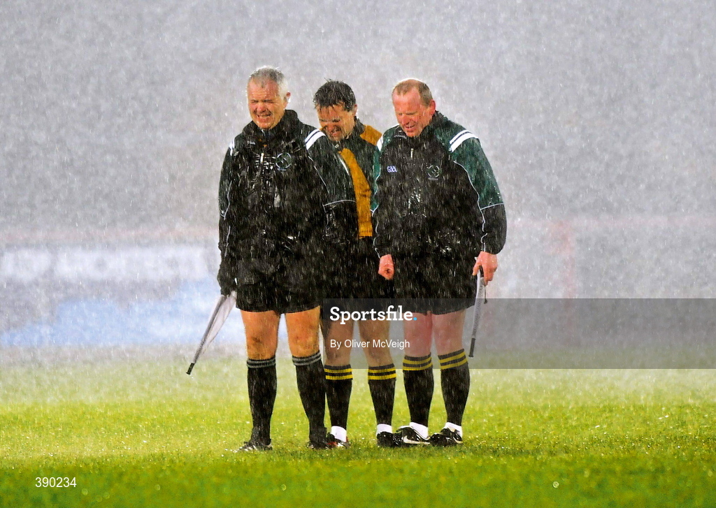 7 March 2009; Men without sense! Match officials, from left, Seamus McGonigle (linesman), Maurice Deegan (referee) and Barry Toland (linesman) brave the torrential rain during the playing of the national anthem before the league game between Galway and Tyrone in Omagh. Picture credit: Oliver McVeigh / SPORTSFILE      This image may be reproduced free of charge when used in conjunction with a review of the book "A Season of Sundays 2009". All other usage © SPORTSFILE