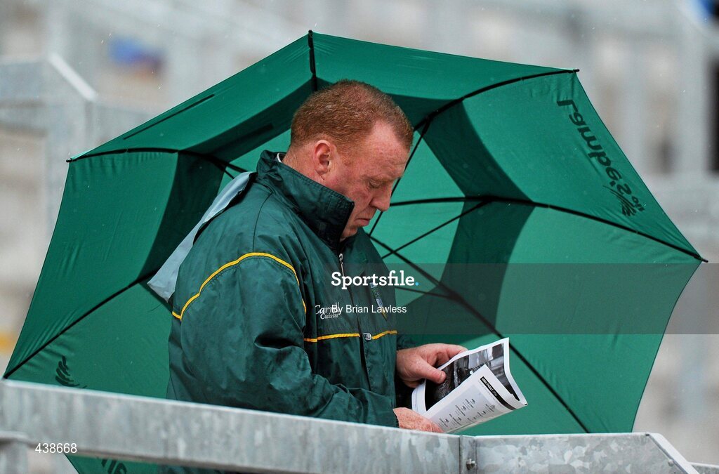 30 June 2010; An Offaly supporter shelters from the rain while reading his programme. ESB Leinster GAA Football Minor Championship Semi-Final, Offaly v Laois, O'Connor Park, Tullamore, Co. Offaly. Picture credit: Brian Lawless / SPORTSFILE