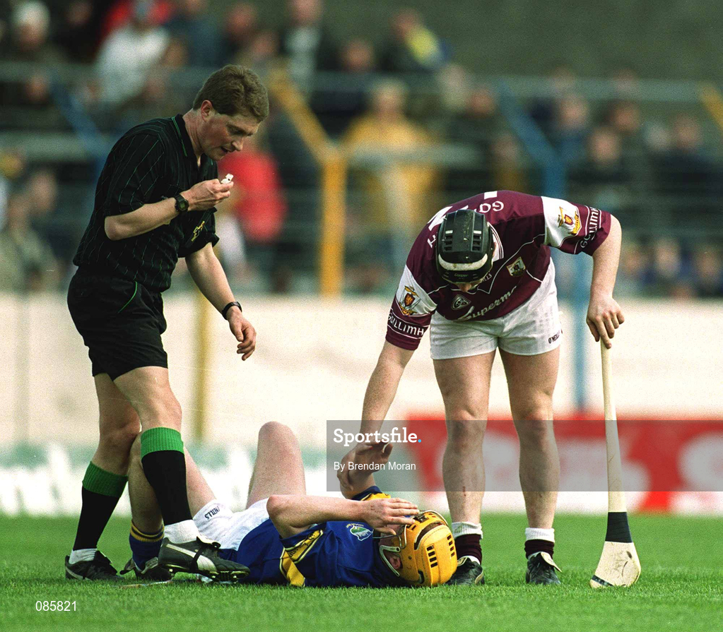 14 April 2002; Eamonn Corcoran of Tipperary lies injured as Eugene Cloonan of Galway and referee Barry Kelly look on during the Allianz National Hurling League Quarter-Final match between Galway and Tipperary at Semple Stadium in Thurles, Tipperary. Photo by Brendan Moran/Sportsfile