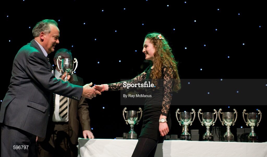 18 February 2012; Kelly Ryan, Ahane GAA Club, Co. Limerick, arrives to collect the cup, from Paddy Naughton, Cathaoirleach, Comhairle Connacht, after winning the 'Solo Singing' competition in the All-Ireland Scór na nÓg Final 2012. Royal Theatre & Events Centre, Castlebar, Co. Mayo. Picture credit: Ray McManus / SPORTSFILE