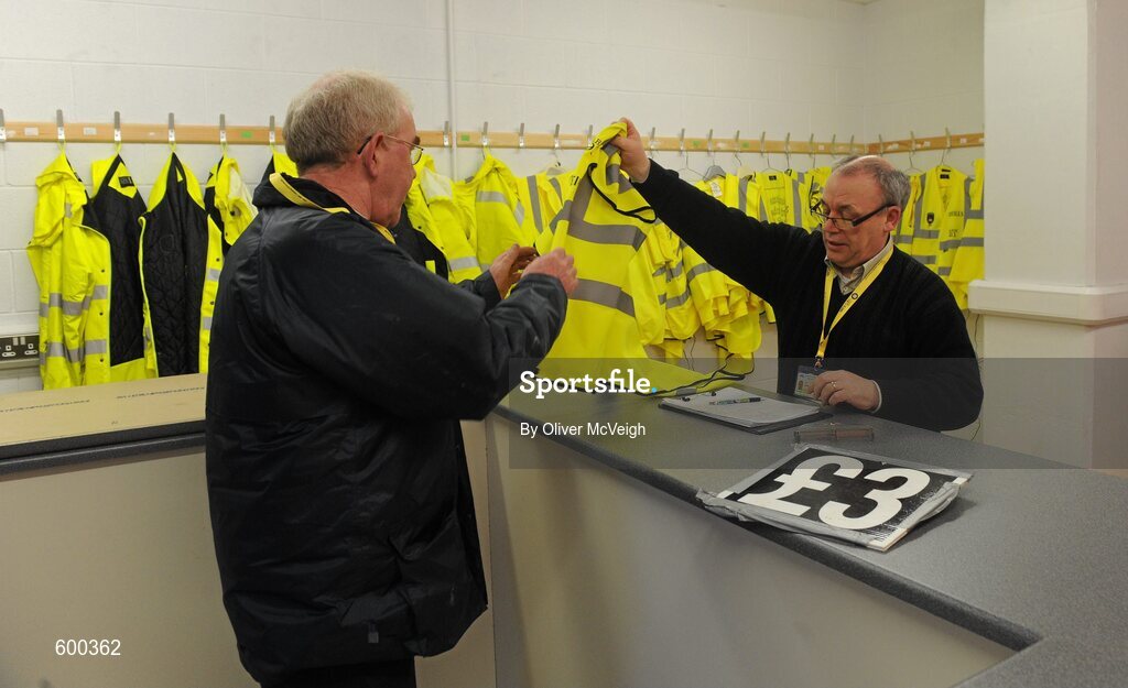 3 March 2012; Conleith Campbell, section supervisor of the stewards at Morgan Athletic Ground, hands a  steward's coat to Peter Rice ahead of the game . Allianz Football League, Division 1, Armagh v Mayo, Morgan Athletic Grounds, Armagh. Picture credit: Oliver McVeigh / SPORTSFILE