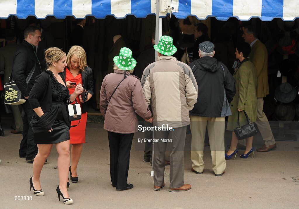 14 March 2012; A couple wearing plastic shamrock hats in attendance during Ladies Day at the Cheltenham Festival. Cheltenham Racing Festival, Prestbury Park, Cheltenham, England. Picture credit: Brendan Moran / SPORTSFILE