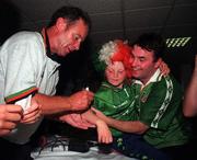 27 July 1998; Republic of Ireland manager Brian Kerr signs an autograph on the arm of Lauren Gibbons, age 7, from Crumlin, as her father, Peter, watches on as the Republic of Ireland UEFA European Under-18 Championship Winning Team Return at Dublin Airport in Dublin. Photo by Matt Browne/Sportsfile