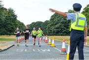 14 July 2018; A member of An Garda Siochana directs runners during the Irish Runner 10 Mile at Phoenix Park in Dublin. Photo by Eoin Smith/Sportsfile