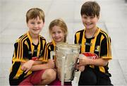 16 August 2019; The Heinrich family, from left, 8 year old Cillian, 5 year old Róisín and 10 year old Cormac living in Sevenoaks, Kent, England, originally from Kells, Kilkenny, with the Liam MacCarthy Cup at the GAA’s Home for the Match stand in the arrivals hall at Dublin Airport. Photo by Ramsey Cardy/Sportsfile