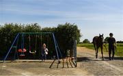 4 June 2020; Jockey Gary Halpin leads Sestriere from the gallops as Faylinn Cummins, aged four, plays on the swings with her puppy Pip at the yard of horse racing trainer Kevin Prendergast in Firarstown in Kildare. Horse racing is due to return to Ireland behind closed doors on June 8, after racing was suspended in an effort to contain the spread of the Coronavirus (COVID-19) pandemic. Photo by Harry Murphy/Sportsfile