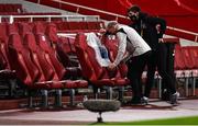 29 October 2020; Dundalk kitman Noel Walsh, accompanied by his son Darragh, places a jersey in the team dugout in commemoration to the late Dundalk team videographer Harry Taaffe prior to the UEFA Europa League Group B match between Arsenal and Dundalk at the Emirates Stadium in London, England. Photo by Ben McShane/Sportsfile