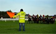 14 December 2020; Racecourse steward Ger Dunne waves a flag at the first causing the field to bypass the jump due to the low sun during the Irish Field 'Supporting Irish Racing' Maiden Hurdle at Naas Racecourse in Kildare. Photo by Seb Daly/Sportsfile