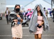 26 July 2021; Racegoers Bernie Grealish, left, and Niamh Glynn shelter from the rain as they arriver to racing on day one of the Galway Races Summer Festival at Ballybrit Racecourse in Galway. Photo by David Fitzgerald/Sportsfile