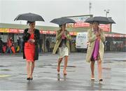 31 July 2013; Racegoers, from left, Clare Wyatt, Robin Greenway and Lucinda Eames, from Devon, England, make their way to the stand in the rain. Galway Racing Festival, Ballybrit, Co. Galway. Picture credit: Barry Cregg / SPORTSFILE