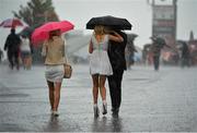 1 August 2013; Racegoers make their way in the pouring rain ahead of the day's races. Galway Racing Festival, Ballybrit, Co. Galway. Picture credit: Barry Cregg / SPORTSFILE