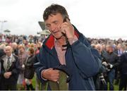 1 August 2013; Trainer Michael Winters speaks to a friend on the phone after he sent out Missunited to win the Guinness Galway Hurdle Handicap. Galway Racing Festival, Ballybrit, Co. Galway.