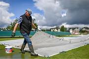 23 May 2022; Eglinton Cricket Club Chairman Ken Craig removes rain covers from the pitch during a rain delay at the Cricket Ireland Inter-Provincial Cup match between North West Warriors and Leinster Lightning at Eglinton Cricket Club in Derry. Photo by Ramsey Cardy/Sportsfile