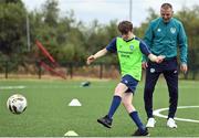 21 July 2022; Participant Jake Malone demonstrates his skills to Republic of Ireland U21 manager Jim Crawford during his visit to the Football For All Summer Soccer School at St Patrick's Boys AFC in Carlow. Photo by Seb Daly/Sportsfile