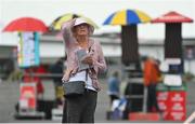 27 July 2022; A racegoer holds her hat in windy conditions as she studies the form in the bookmakers' enclosure prior to racing on day three of the Galway Races Summer Festival at Ballybrit Racecourse in Galway. Photo by Seb Daly/Sportsfile