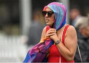 29 July 2022; A racegoer shelters from the rain prior to racing on day five of the Galway Races Summer Festival at Ballybrit Racecourse in Galway. Photo by Seb Daly/Sportsfile
