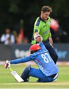 9 August 2022; Usman Ghani of Afghanistan is helped to his feet by Mark Adair of Ireland during the Men's T20 International match between Ireland and Afghanistan at Stormont in Belfast. Photo by Ramsey Cardy/Sportsfile