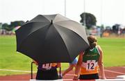 13 August 2022; Girls take shelter with an umbrella during the u14 shot put final at the Aldi Community Games National Track and Field Finals that attract over 2,000 children to SETU Carlow Sports Campus in Carlow. Photo by Ramsey Cardy/Sportsfile