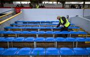 15 January 2023; Steward Frank Lyons, from Ruan GAA club in Clare, wipes down the wet seats at the substitutes bench before the Co-Op Superstores Munster Hurling League Group 1 match between Clare and Waterford at Cusack Park in Ennis, Clare. Photo by Brendan Moran/Sportsfile