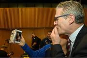 17 February 2023; Jarlath Burns stands with his sister Bronwyn Traynor as he blows kisses to his mother Helen Burns and sister Helena Burns on FaceTime after he was voted-in as the GAA president elect during day one of the GAA Annual Congress 2023 at Croke Park in Dublin. Photo by Piaras Ó Mídheach/Sportsfile
