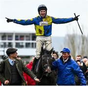 15 March 2023; Jockey Harry Skelton celebrates on Lander Dan, as they are led into the winners enclosure by owner Colm Donlon, left, and groom Stephen Petch, right, after winning the Coral Cup Handicap Hurdle during day two of the Cheltenham Racing Festival at Prestbury Park in Cheltenham, England. Photo by Harry Murphy/Sportsfile