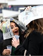 15 March 2023; Racegoers cover their heads from the rain with a newspaper during day two of the Cheltenham Racing Festival at Prestbury Park in Cheltenham, England. Photo by Harry Murphy/Sportsfile