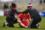 19 March 2023; Shane McGuigan of Derry receives medical attention after a foul from Ciarán Russell of Clare, not pictured, during the Allianz Football League Division 2 match between Derry and Clare at Derry GAA Centre of Excellence in Owenbeg, Derry. Photo by Ben McShane/Sportsfile