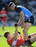 2 April 2023; Brendan Rogers of Derry is helped to his feet by Lee Gannon of Dublin during the Allianz Football League Division 2 Final match between Dublin and Derry at Croke Park in Dublin. Photo by Ramsey Cardy/Sportsfile