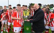 15 April 2023; St Joseph’s captain Scott Higgins is presented with the trophy by FAI president Gerry McAnaney after the FAI Youth Cup Final match between St Joseph’s AFC, Dublin, and College Corinthians AFC, Cork, at the Carlisle Grounds in Bray, Wicklow. Photo by Seb Daly/Sportsfile