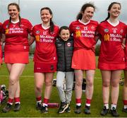 30 April 2023; Team mascot Donal Moohan, 10, from Edendork GAA stands with Tyrone players, from left, Cora Quinn, Áine Cunningham, Catherine Moohan, and Aoife Gildernew after the Electric Ireland Camogie Minor C All-Ireland Championship Shield Final match between Donegal and Tyrone at Tír na nÓg Randalstown in Antrim. Photo by Stephen Marken/Sportsfile