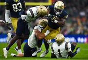 26 August 2023; Notre Dame running back Audric Estimé is tackled by Navy players Mbiti Williams Jr and Jaxson Campbell during the Aer Lingus College Football Classic match between Notre Dame and Navy Midshipmen at the Aviva Stadium in Dublin. Photo by Brendan Moran/Sportsfile