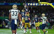 26 August 2023; Notre Dame wide receiver Deion Colzie #0, top, celebrates with teammates after scoring their side's sixth touchdown during the Aer Lingus College Football Classic match between Notre Dame and Navy Midshipmen at the Aviva Stadium in Dublin. Photo by Brendan Moran/Sportsfile