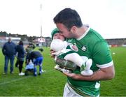 21 October 2023; Niall Arthur of Ireland and his daughter Annabelle, age four months, celebrate with the Mowi Quaich after the 2023 Hurling Shinty International Game between Ireland and Scotland at Páirc Esler in Newry, Down. Photo by Piaras Ó Mídheach/Sportsfile