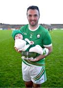 21 October 2023; Niall Arthur of Ireland and his daughter Annabelle, age four months, celebrate with the Mowi Quaich after the 2023 Hurling Shinty International Game between Ireland and Scotland at Páirc Esler in Newry, Down. Photo by Piaras Ó Mídheach/Sportsfile
